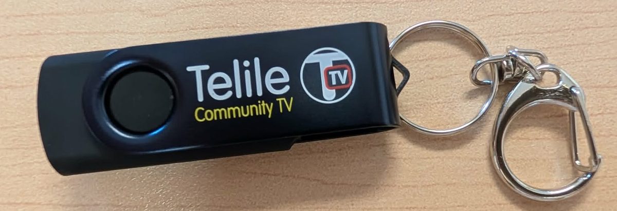 A black Telile Community TV USB stick on a keyring